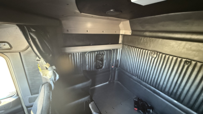 Kenworth W900 truck cab interior showing sleeper area with ribbed side panels and storage compartments.