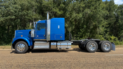 Kenworth W900 on road with blue cab and chrome fuel tanks, side profile view.