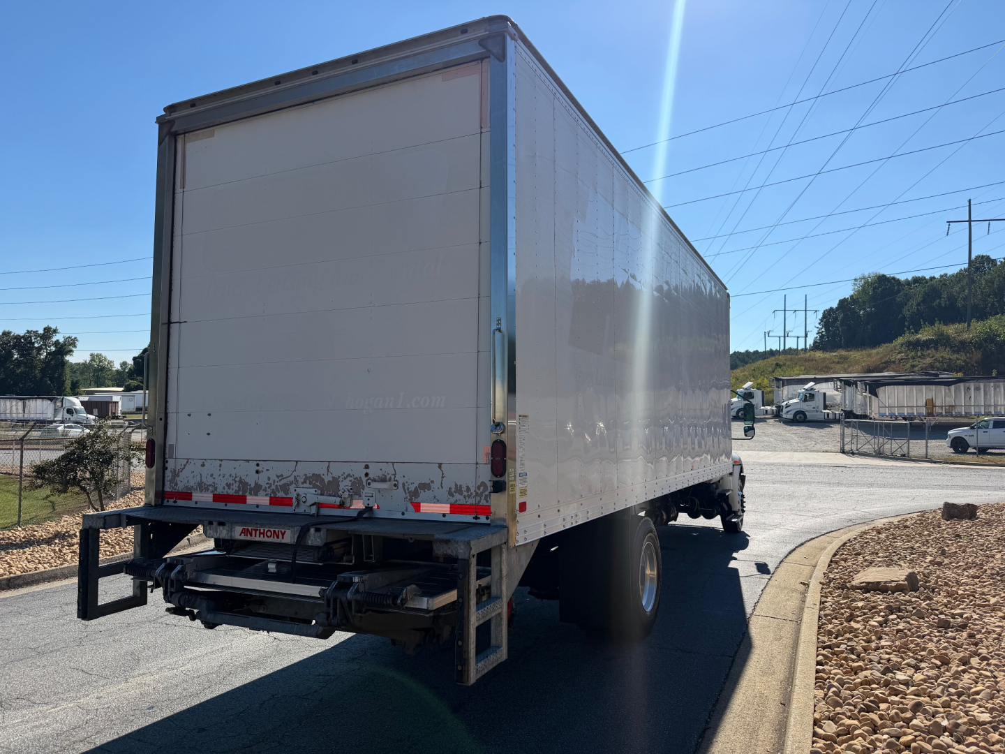 Box truck exterior rear view showing cargo box and rear bumper; side panels with reflective tape and rear lights visible.