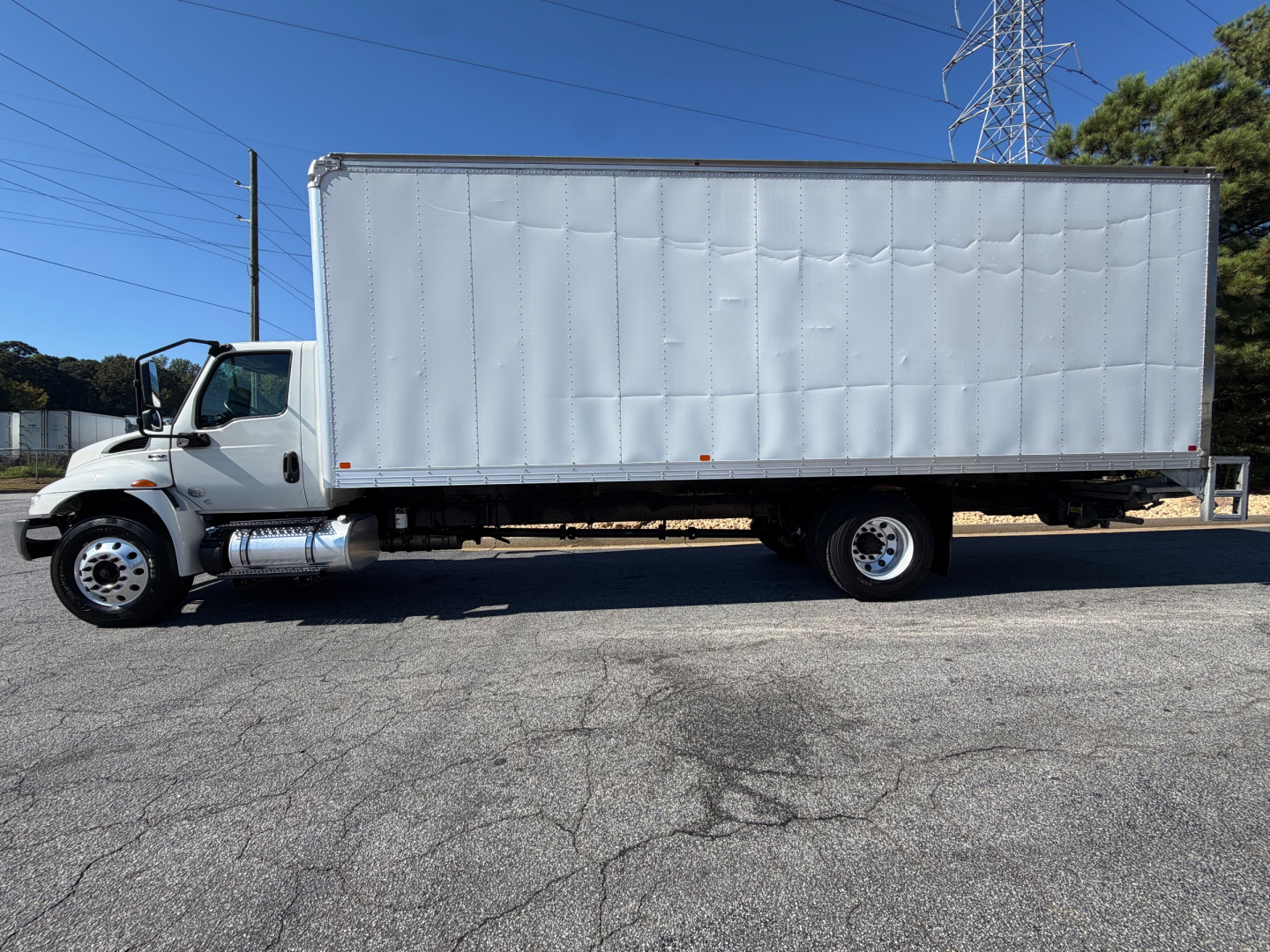 Box truck side view showing a large white cargo box on a white International MV series chassis with front cab and dual rear wheels.
