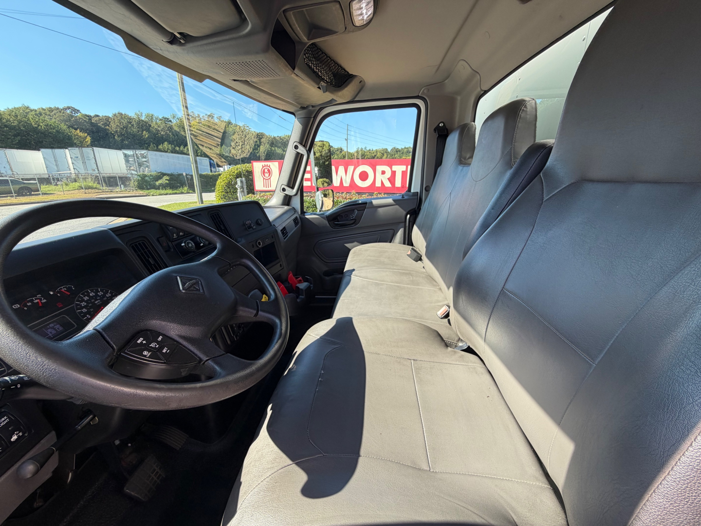 Truck cab interior showing dashboard steering wheel and long bench seat in a 2022 International MV607.