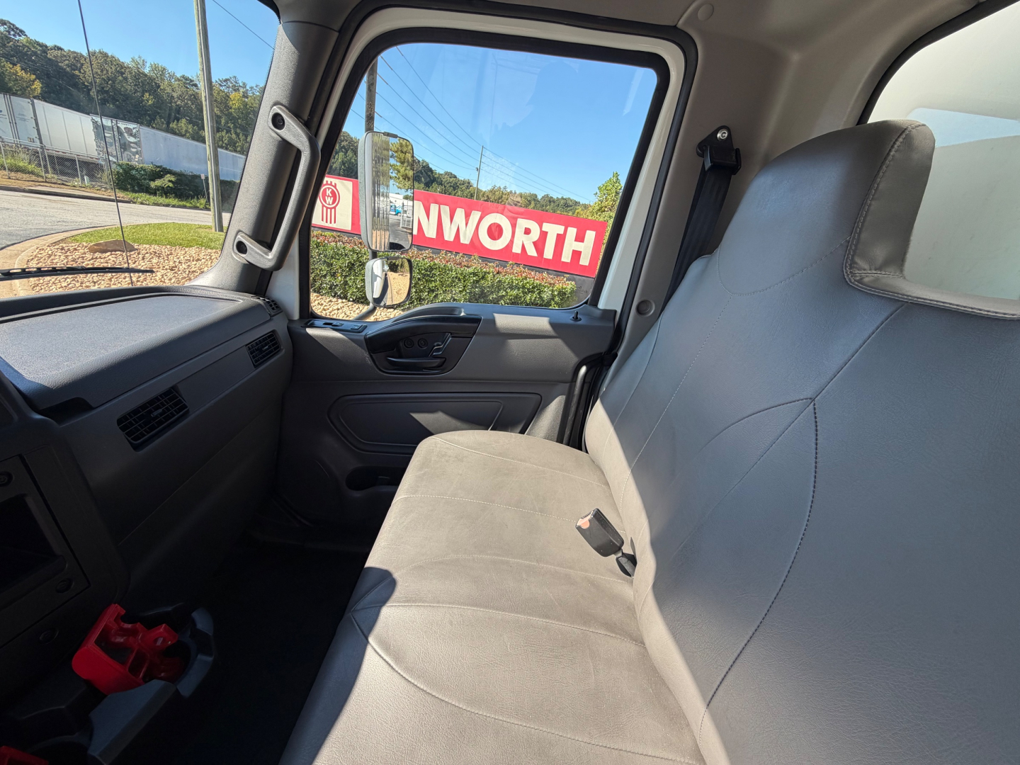 Truck interior cab view of a 2022 International MV607 with gray bench seat, steering wheel, and side door panel visible.