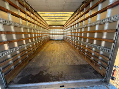 Interior of an empty box truck cargo area with wooden side rails and metal tracks, showing a wooden floor and front wall.
