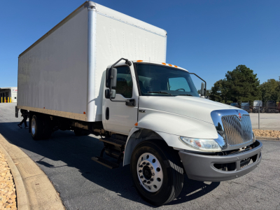 Box truck with a white cab and large rectangular box, International MV series, front-right view, VIN 3HAEUMML7NL681138, stock 0633514, with tandem rear wheels and clear blue sky.