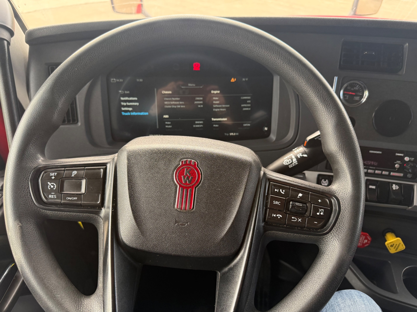 Kenworth T680 dash and steering wheel view inside cabin showing center touchscreen display and steering wheel controls.