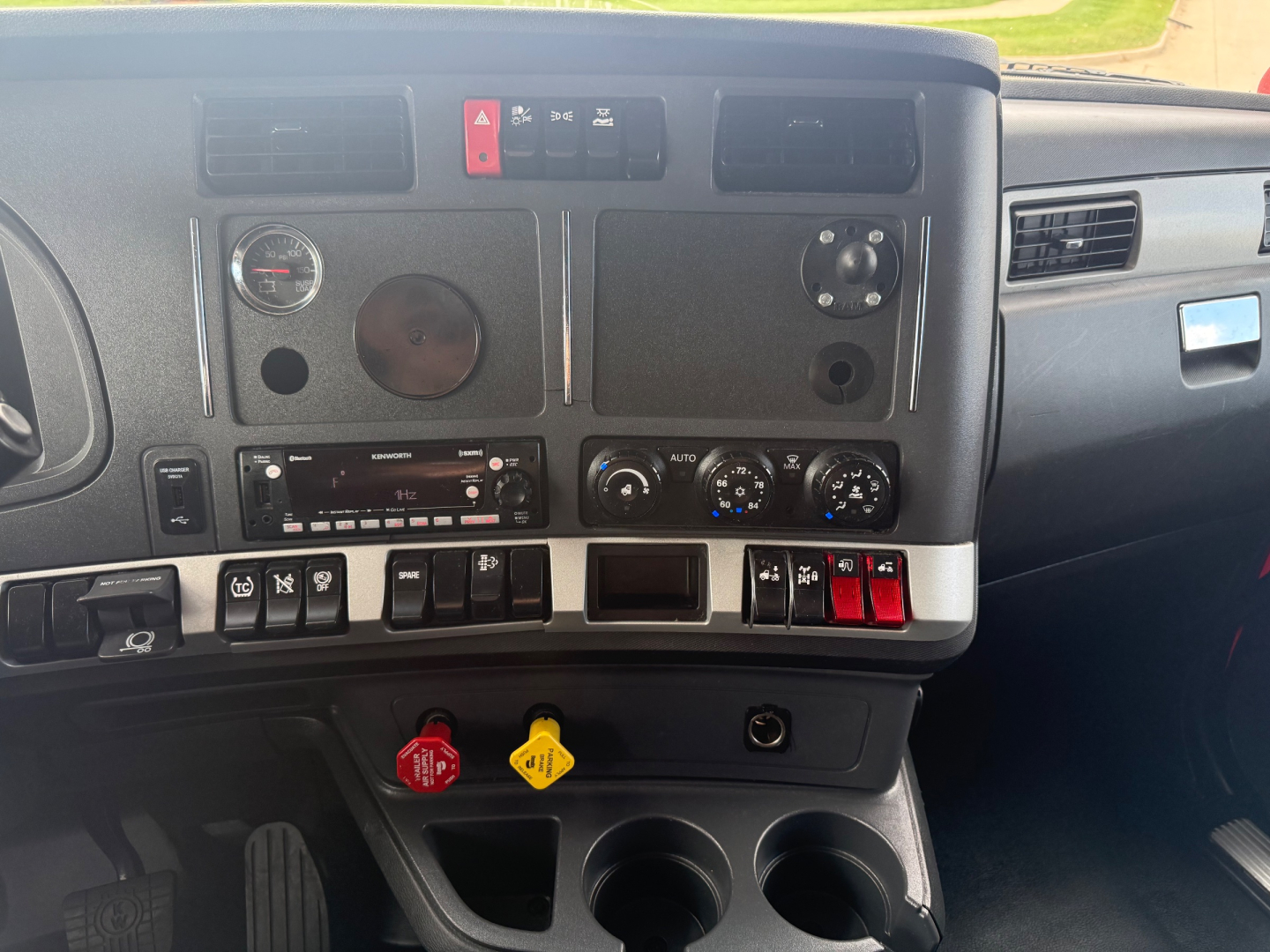 Dashboard of a Kenworth truck showing gauges, controls, and vents visible in the cab interior.