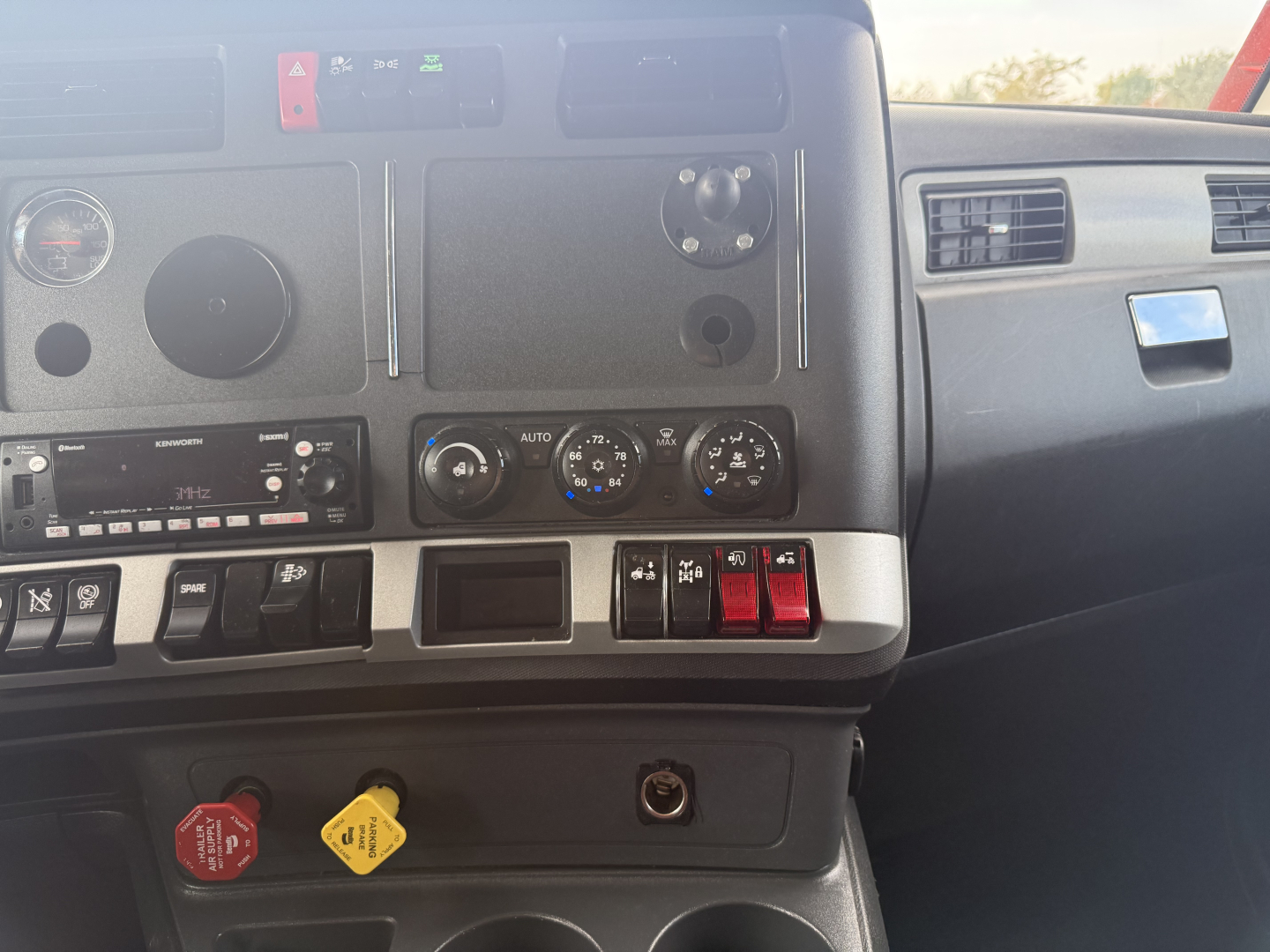 Kenworth T680 dashboard with controls, vents, and knobs visible; dashboard switches, climate controls, and a circular gauge area shown.