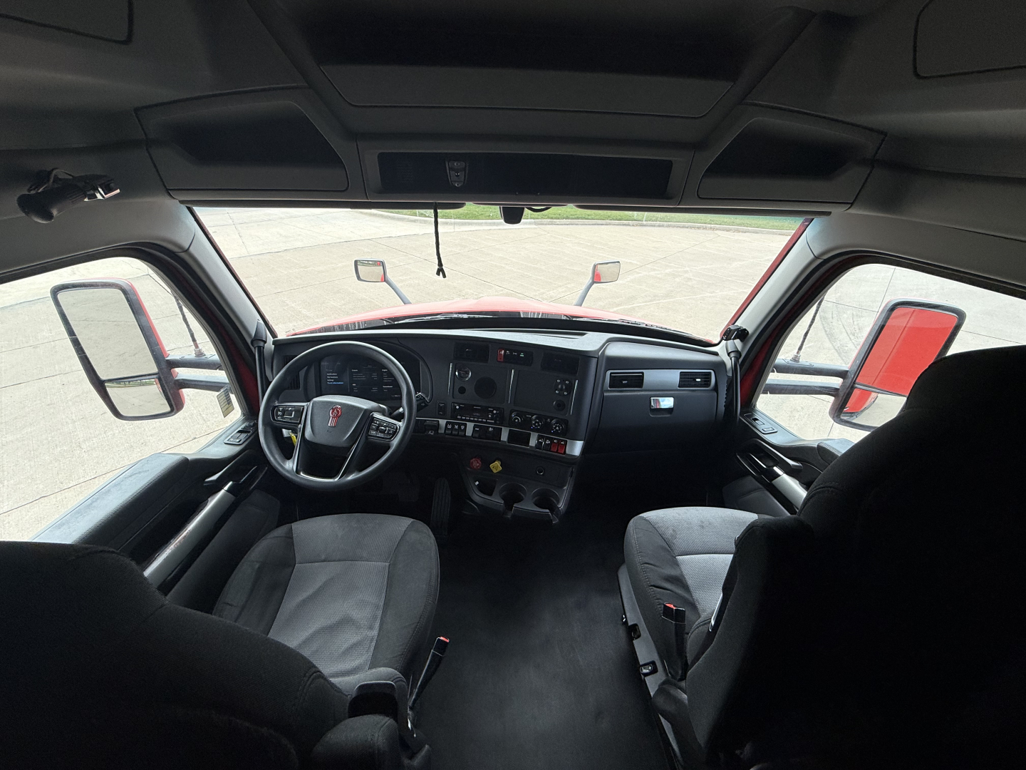 Interior view of a Kenworth T680 truck cab with steering wheel, dashboard, and seating visible.