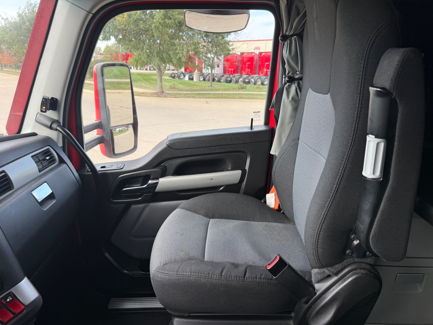 Kenworth T680 interior driver seat area showing cabin, door panel, and side mirror view.