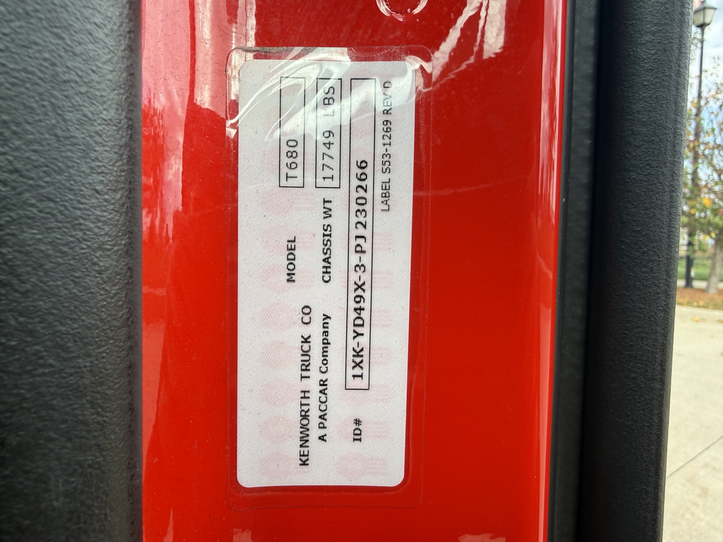 Label on red Kenworth truck door jamb with model and serial information: MODEL T680, CHASSIS 9177499 (or 177449), factory labels, barcodes, and VIN 1XKYD49X3PJ230266.