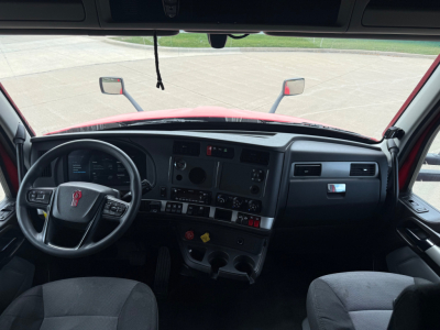 Kenworth T680 cab interior showing steering wheel and dashboard with various gauges and controls.