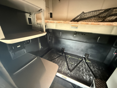 Kenworth T680 cab sleeper interior showing storage area with bed, side panel, and floor with harnessed straps.