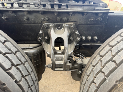 Kenworth T680 chassis center showing fifth wheel and suspension link between dual rear axles, with visible bolts and air lines.