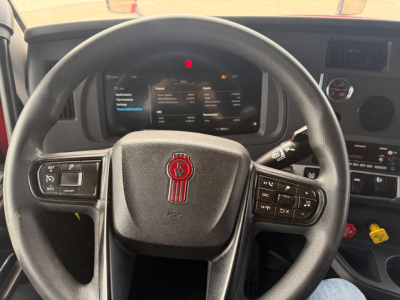Kenworth T680 dash and steering wheel view inside cabin showing center touchscreen display and steering wheel controls.