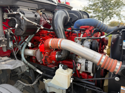 Kenworth T680 engine bay showing red engine block with turbocharger piping, hoses, and coolant reservoir