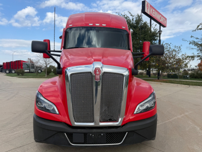 Kenworth T680 front view showing bold chrome grille with Kenworth emblem, red hood and bumper, black lower fascia, and side mirrors.