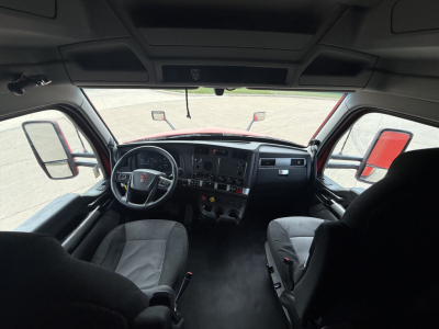 Interior view of a Kenworth T680 truck cab with steering wheel, dashboard, and seating visible.