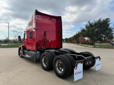 Kenworth T680 tractor rear doors and fifth wheel view with dual rear axles, red cab, stock tag, and trailer mud flaps visible.