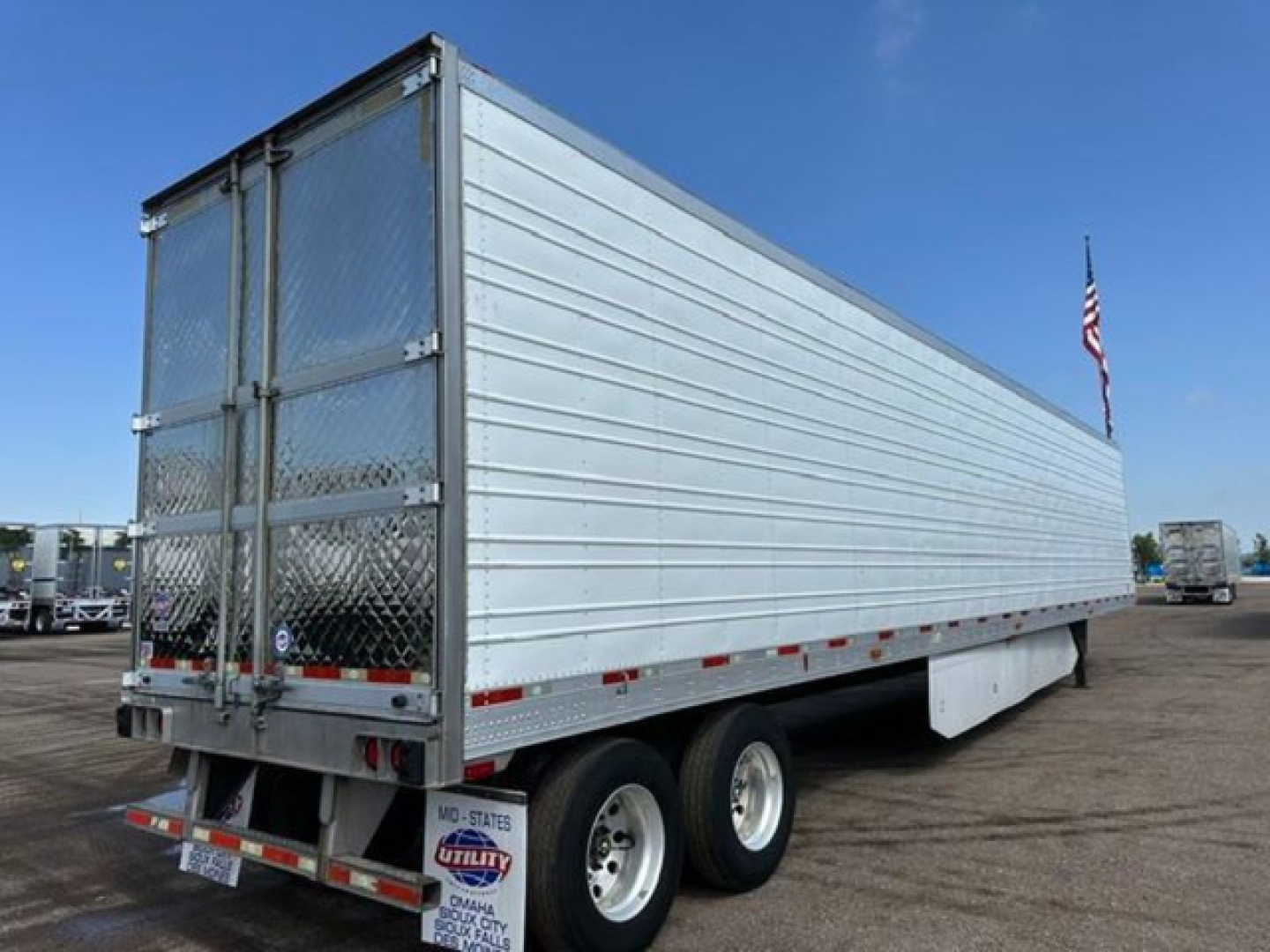 Utility reefer trailer side and rear view showing aluminum panel walls, tandem axles, rear doors, and reflective tape.