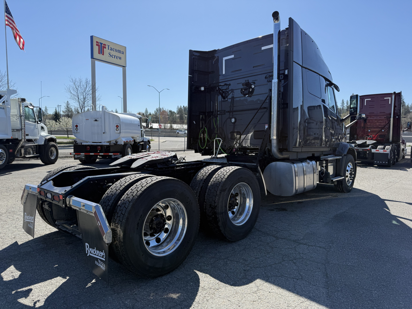 Truck chassis and cab of a 2027 Mack AN64T64 conventional sleeper showing rear dual axles and fifth wheel in an outdoor lot.