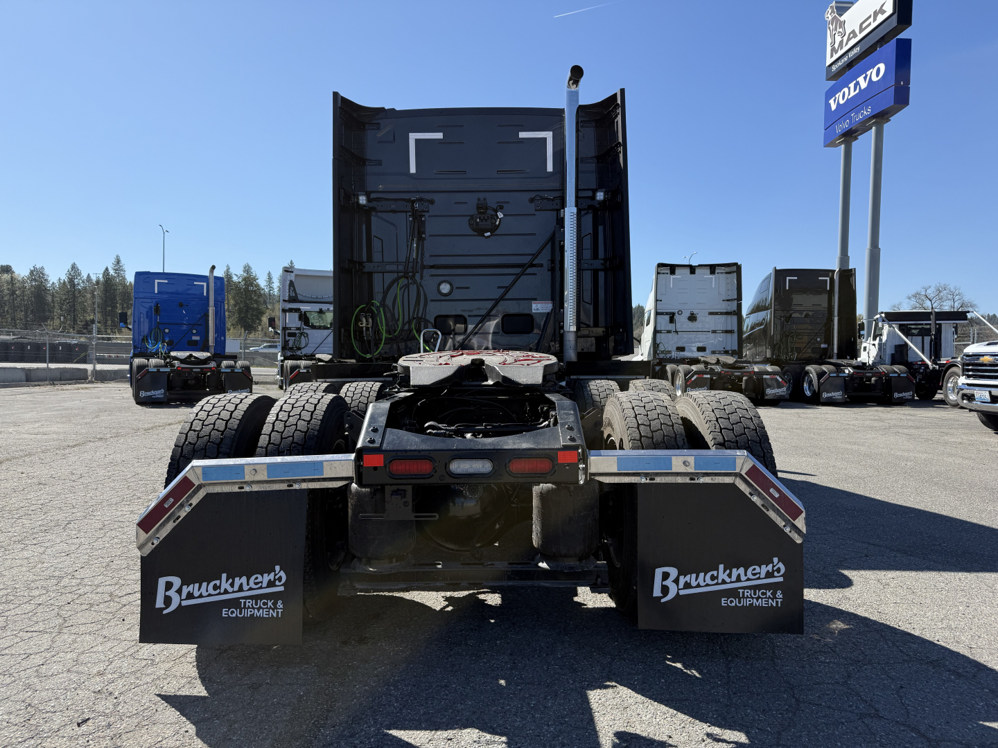 Truck chassis rear view showing dual rear axles and mud flaps with Brueckner Equipment branding, 2027 Mack AN64T64 listing.
