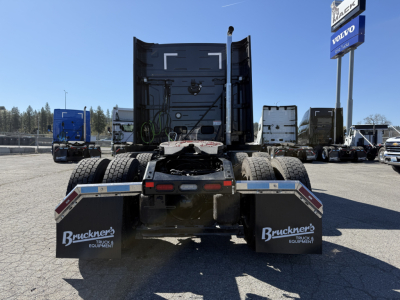 Truck chassis rear view showing dual rear axles and mud flaps with Brueckner Equipment branding, 2027 Mack AN64T64 listing.