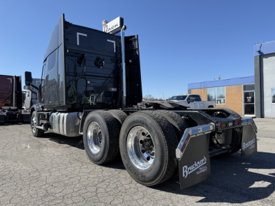 Mack AN64T64 conventional sleeper truck chassis rear view showing dual rear axles and mud flaps with Buckner's logo.