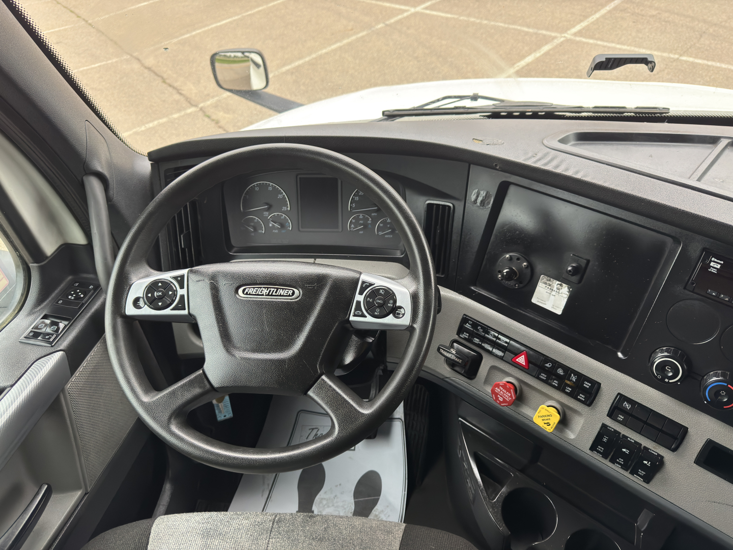 Truck interior cockpit of a Freightliner Cascadia 126 showing steering wheel, gauges, and driver-side controls.