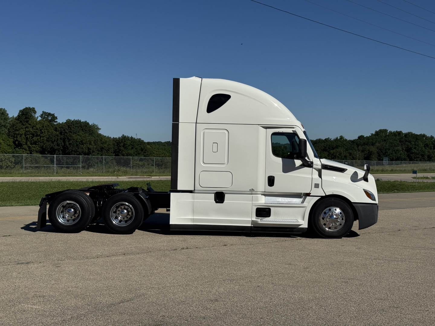 Freightliner Cascadia 126 tractor in side profile view showing sleeper cab, white exterior, dual rear axles, and chrome wheels.