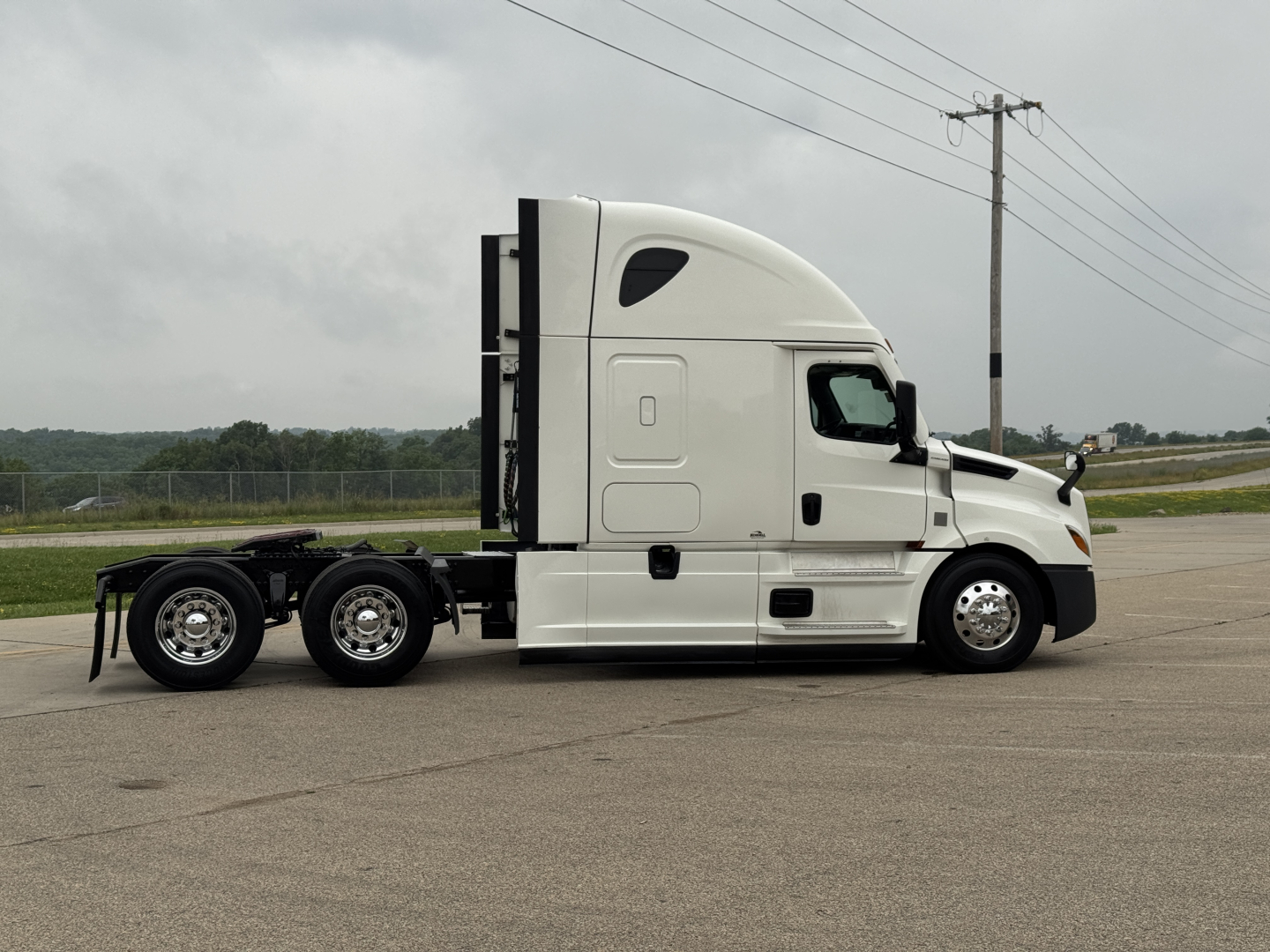 Freightliner Cascadia 126 sleeper cab truck side view showing chassis and tractor with white paint.
