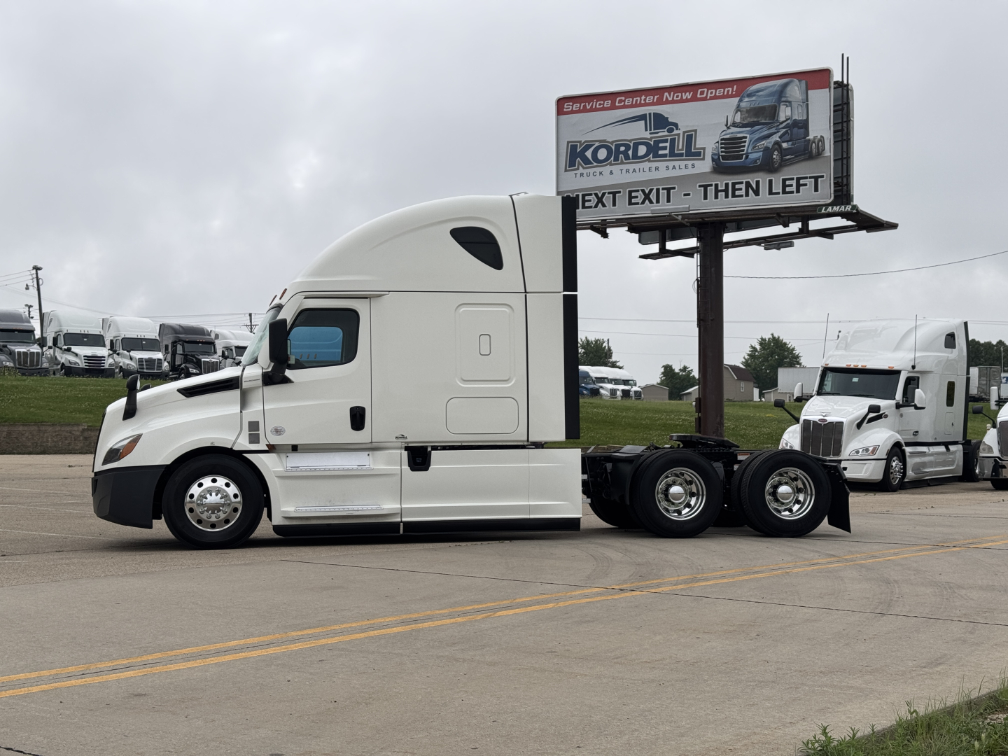 Truck side view of a 2021 Freightliner Cascadia 126 tractor with sleeper, white color, showing a semi-trailer hitch and dual rear axles.