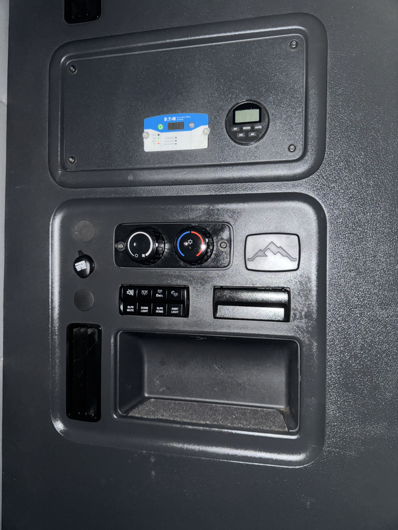 Dashboard panel in a Freightliner Cascadia showing climate controls and a small gauge/driver display.