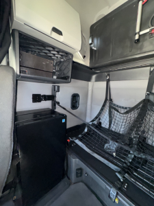 Cab interior showing storage shelf and netted cargo area in a Freightliner Cascadia sleeper