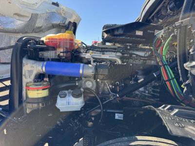 Freightliner Cascadia 126 engine bay showing coolant reservoir, blue hose, and various wiring harnesses.