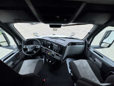 Cab interior of a Freightliner Cascadia truck showing dashboard, steering wheel, and front seats.