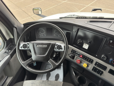 Truck interior cockpit of a Freightliner Cascadia 126 showing steering wheel, gauges, and driver-side controls.