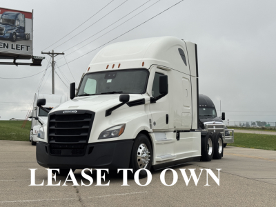 Truck cab of a white Freightliner Cascadia 126 semi-truck with the words 'LEASE TO OWN' across the front grille area.