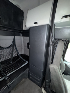 Cascadia 126 truck cabin interior showing sleeper area with storage cabinet and netting, entering from side door.