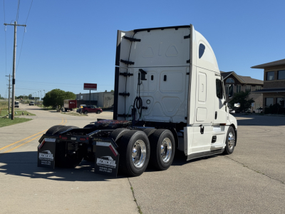 Truck tractor rear three-quarter view showing cab and dual rear axles with white paint and black mud flaps.