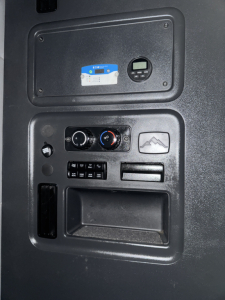 Dashboard panel in a Freightliner Cascadia showing climate controls and a small gauge/driver display.