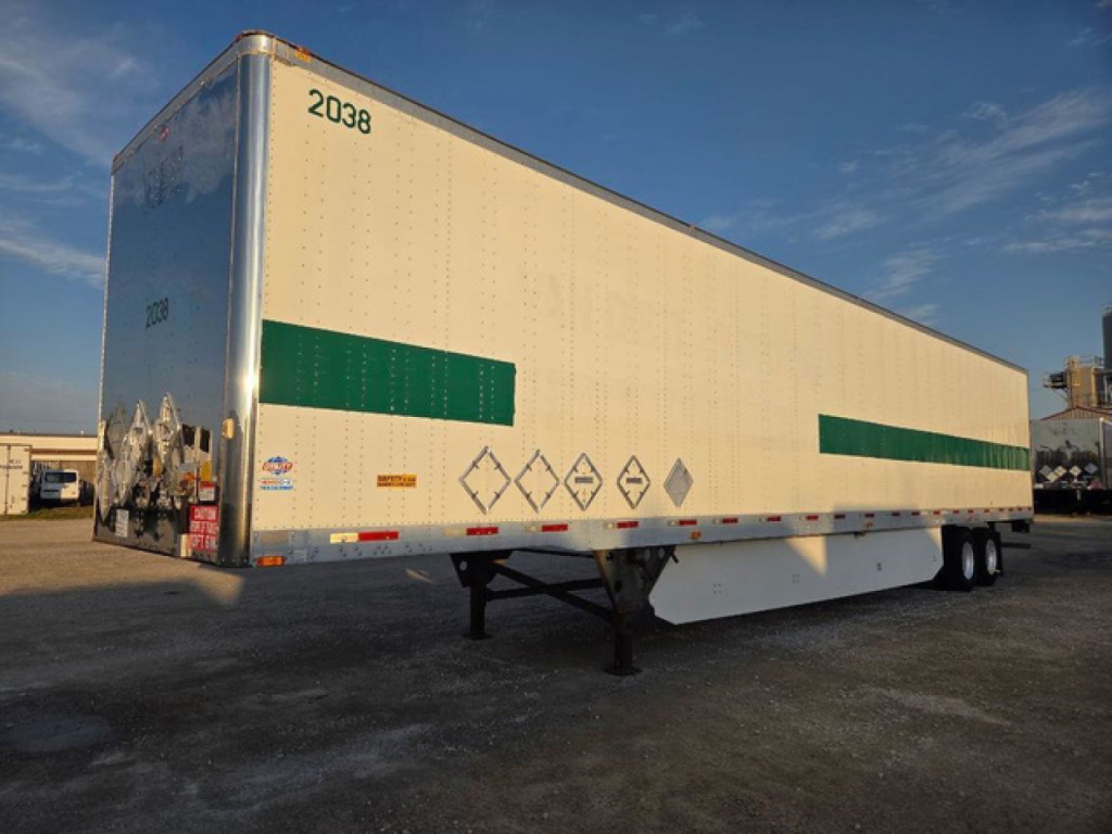 Trailer side view showing dry van trailer with green reflective bands and safety placards and supporting landing gear.
