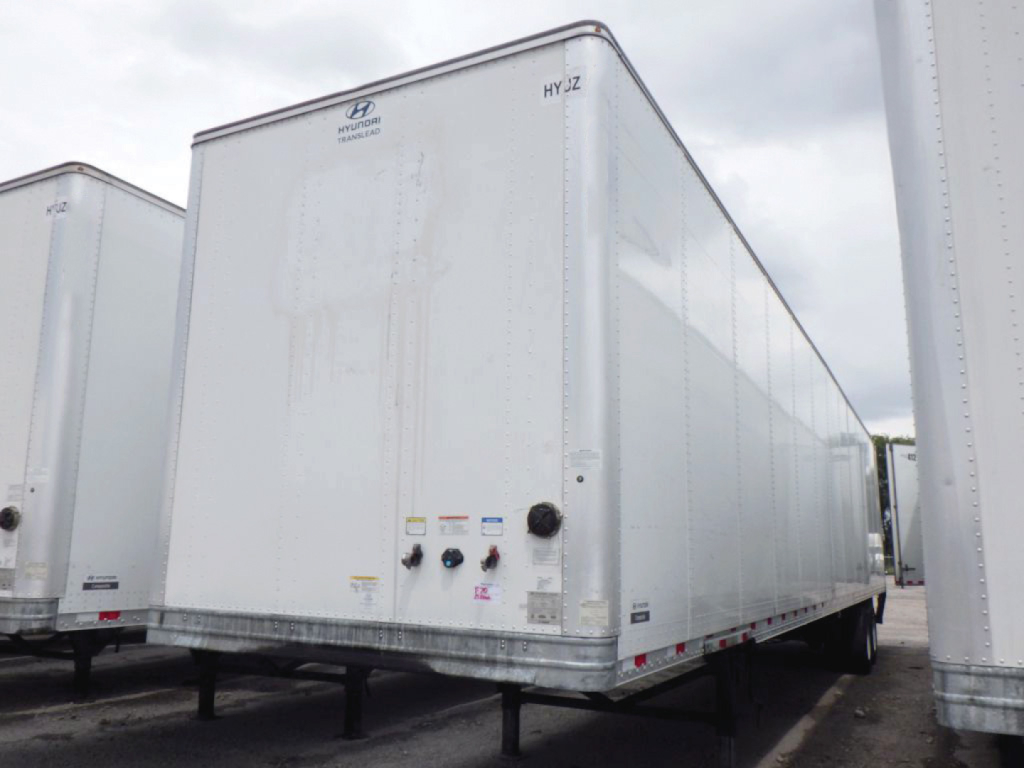Tall white Hyundai Translead trailer with rear doors and rear lights, front left view showing small control ports and labels on the lower front panel.