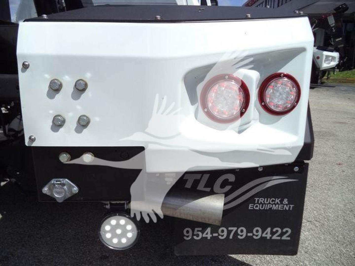 Truck rear showing white enclosure, two red circular taillights, multiple bolts, and TCL Truck & Equipment logo with contact number.