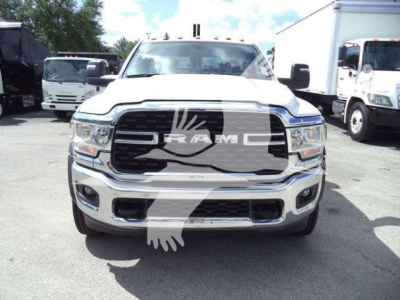 Front view of a white 2024 Ram 4500 SLT truck showing RAM grille and bumper, with side mirrors and other trucks in background.