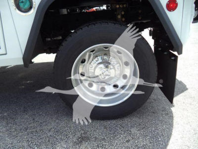 Wheel and tire close-up on a Ram 4500 pickup showing a polished steel wheel and heavy-duty tire; partial undercarriage and fender visible.