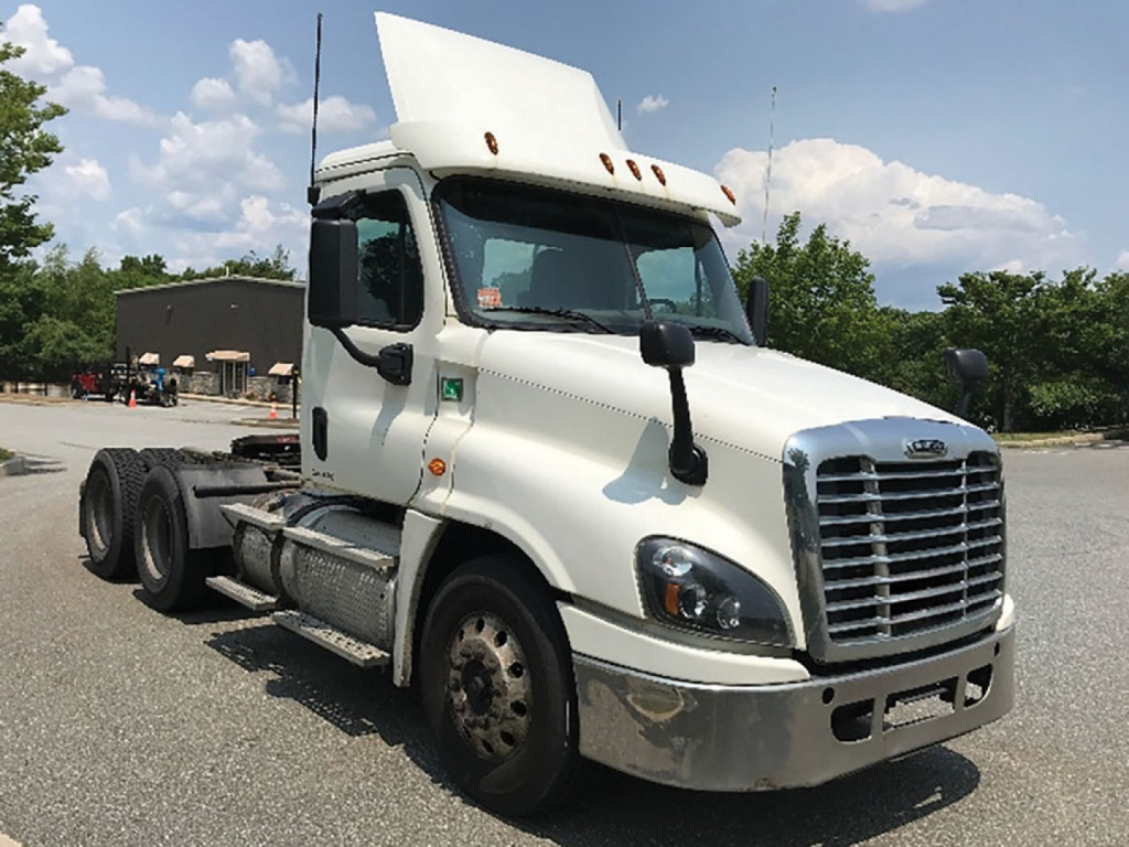 Truck cab of a 2018 Freightliner Cascadia125 daycab with a raised hood, white exterior, and front chrome bumper.