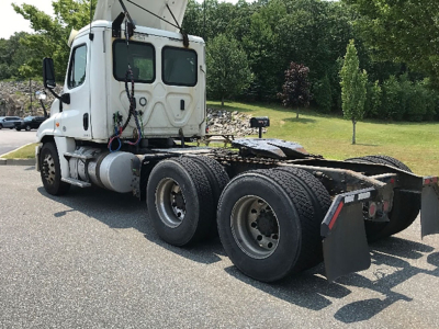 Freightliner Cascadia125 tractor truck 6x4 chassis shown from rear-left, white cab, dual rear axles, sleeper cab, fuel tanks, exposed fifth wheel area.