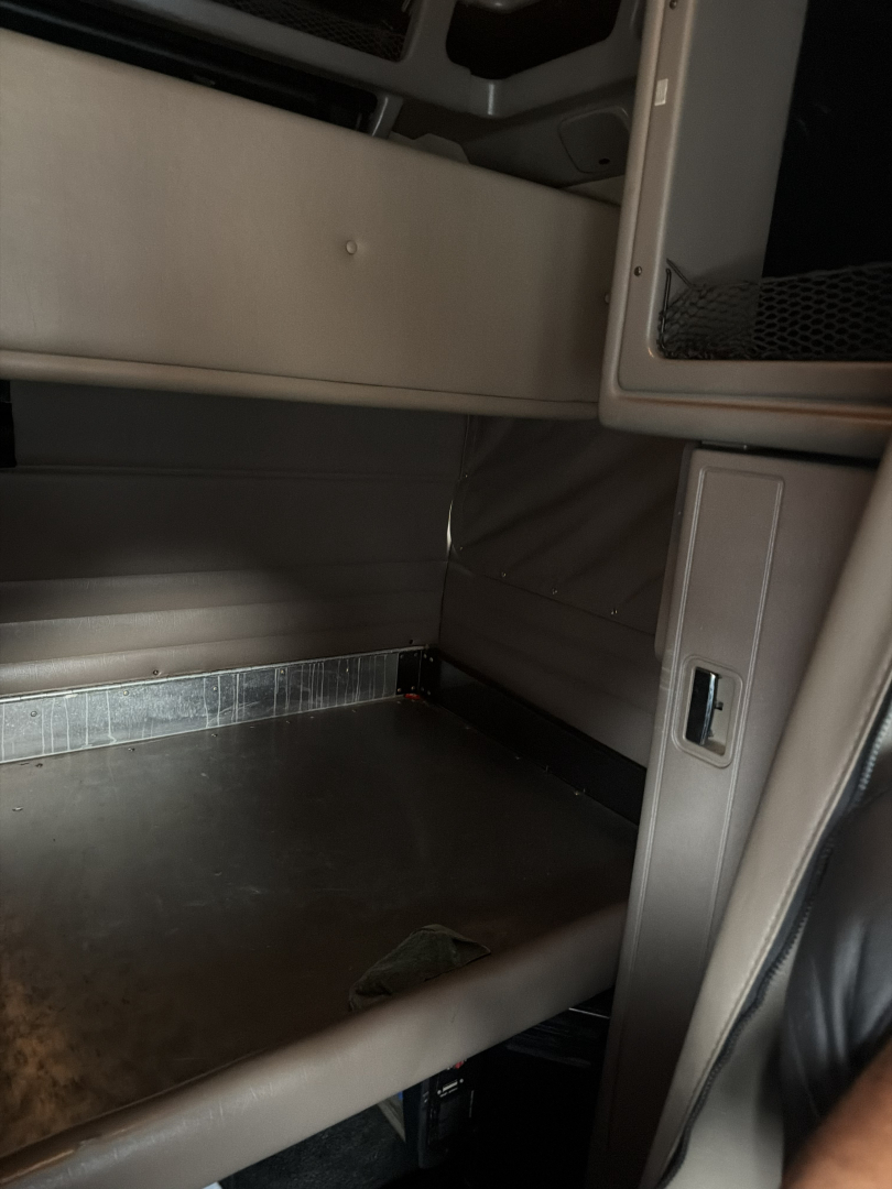 Truck cab interior of a Peterbilt 389 sleeper showing cabin entry area and lower cargo space.
