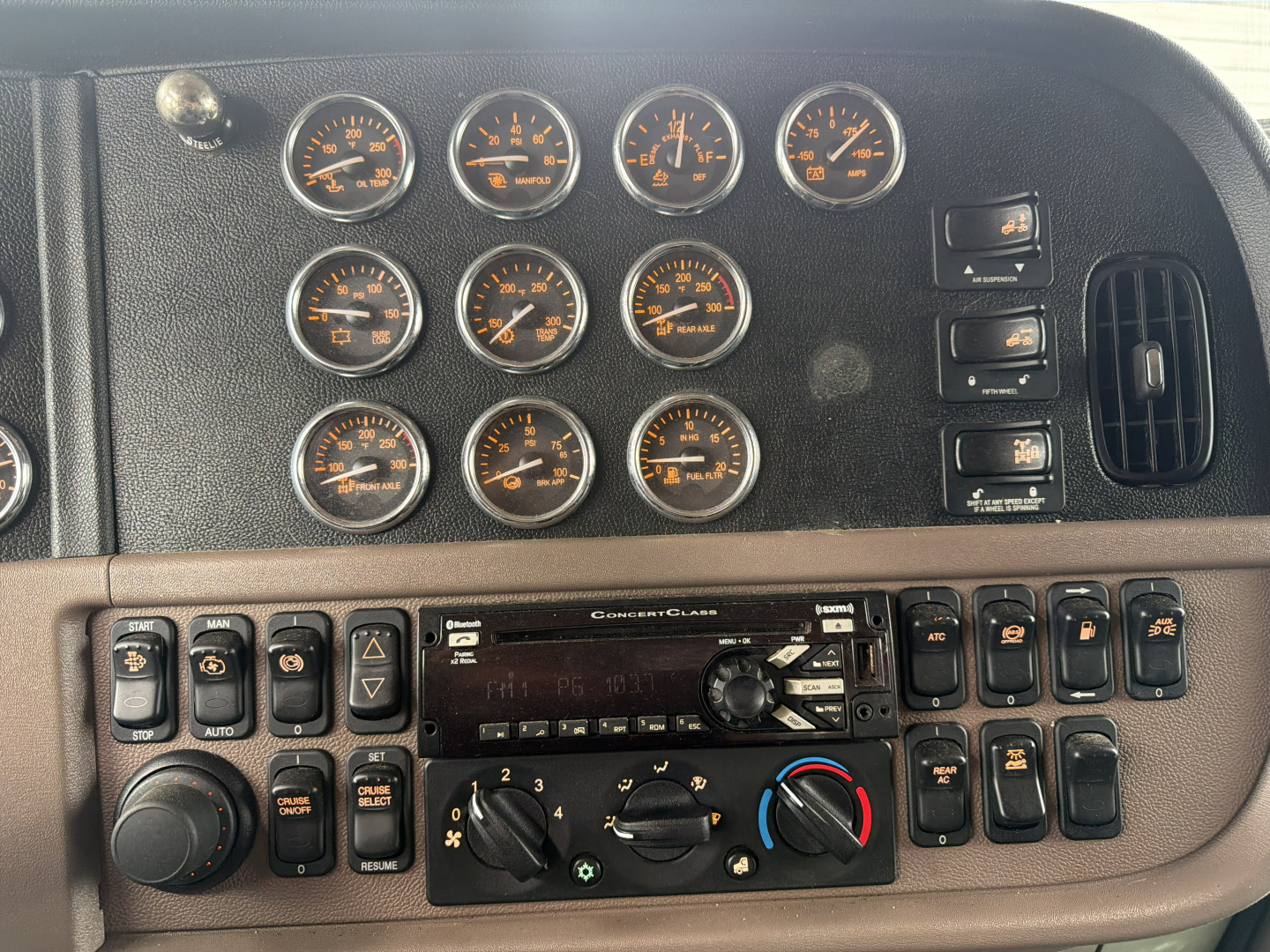Peterbilt 389 dashboard and instrument cluster with multiple gauges and control switches in view.
