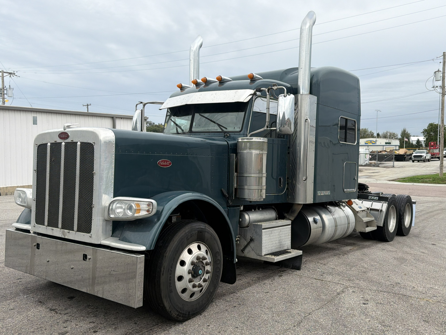 Peterbilt 389 truck in side view with sleeper cab, chrome exhaust stacks, and large chrome bumper. Diesel twin tanks visible, front grille, headlights, and wheels. US-spec truck with dark teal paint.